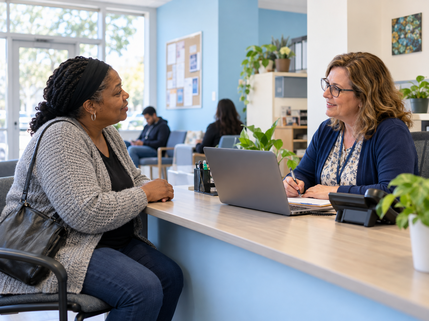 A visitor speaking with a welcoming community helper at a desk.